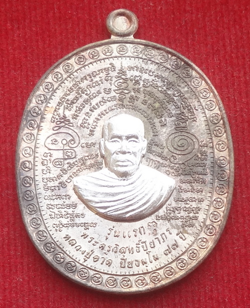 เหรียญรุ่นแรก แพะคู่มิตรชนะจิตคน หลวงปู่อาด วัดบุญสัมพันธ์ จ.ชลบุรี ปลุกเสกเดี่ยว 77 วัน พิธีใหญ่ วันวิสาขบูชาราชาฤกษ์ ที่ 14 พฤษภาคม 2556 เนื้อนวะแก่เงิน หน้ากากเงิน หมายเลข ๑๖๕ (แยกชุดกรรมการ) ขนาดเหรียญรวมห่วงตัน 3.0 x 4.1 ซ.ม. จำนวนสร้าง 377 ชุด (1 ชุด มีเหรียญเนื้อนวะหน้ากากเงิน 1 เหรียญ เนื้อตะกั่วรองพิมพ์ไม่ตัดปีก 3 เหรียญ เนื้อทองฝาบาตร 3 เหรียญ ทั้งชุดตอกโค๊ตและหมายเลขเดียวกัน ๑๖๕)